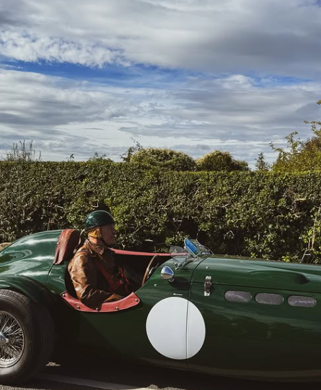A driver in a green vintage sports car