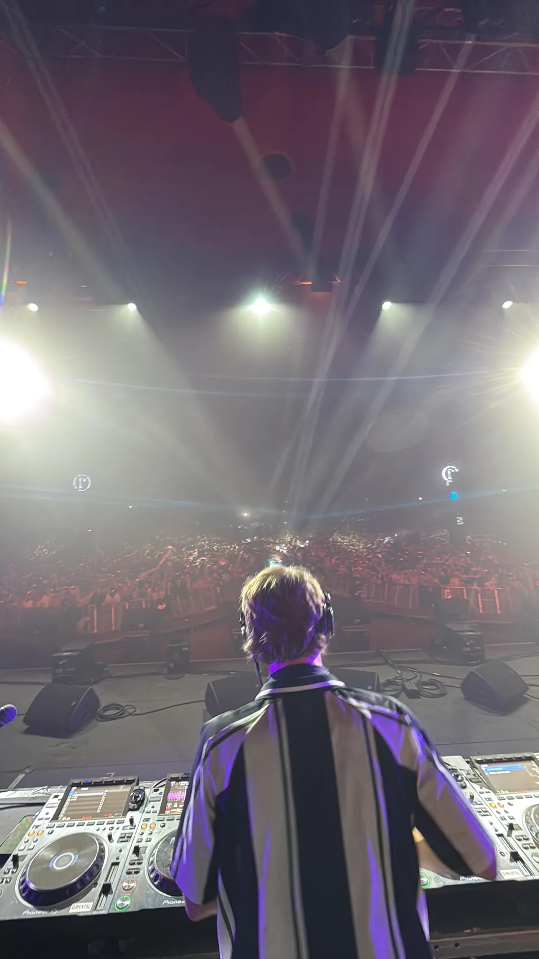 A packed crowd seen from behind the DJ booth